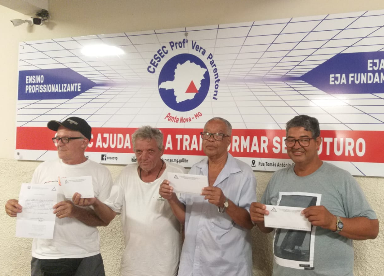 4 homens, 1 de meia-idade e 3 idosos, lado a lado para a foto, segurando um certificado em frente ao corpo. Dois deles são negros, um é pardo e um é branco.