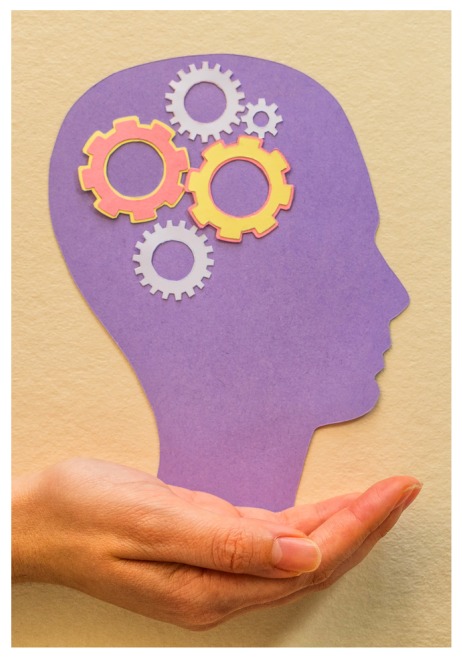 Desenho roxo de uma cabeça de perfil virada para a direita, apoiada sobre a mão de uma pessoa de pele branca. Dentro da cabeça, na região do crânio, há desenhos de engrenagens de diferentes tamanhos e cores.