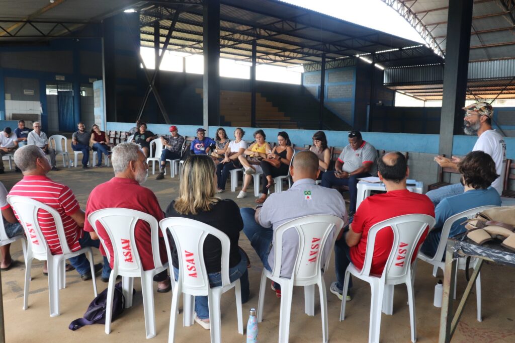 Dezenas de pessoas de diferentes, gêneros, idades e etnias, sentadas em círculo.