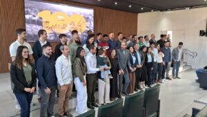 Componentes da mesa de autoridades e servidores recém-empossados, organizados em duas fileiras. Estão todos de pé, lado a lado, para a foto.