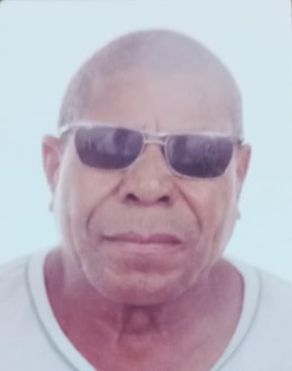 Foto de Ze Tito: homem negro, calvo, rosto redondo, nariz largo. Ele usa óculos escuros e tem a expressão séria.